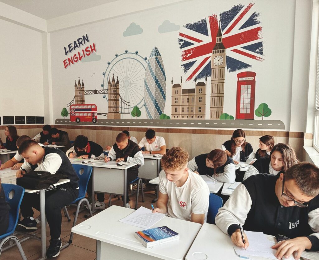 pexels photo 29242202 Students studying English in a classroom with British themed decor and mural.